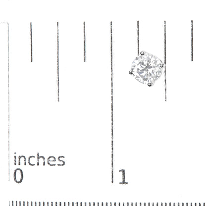 Close-up front view of a single white metal earring with a round white gemstone in a 4-prong setting, placed on a ruler for size reference.