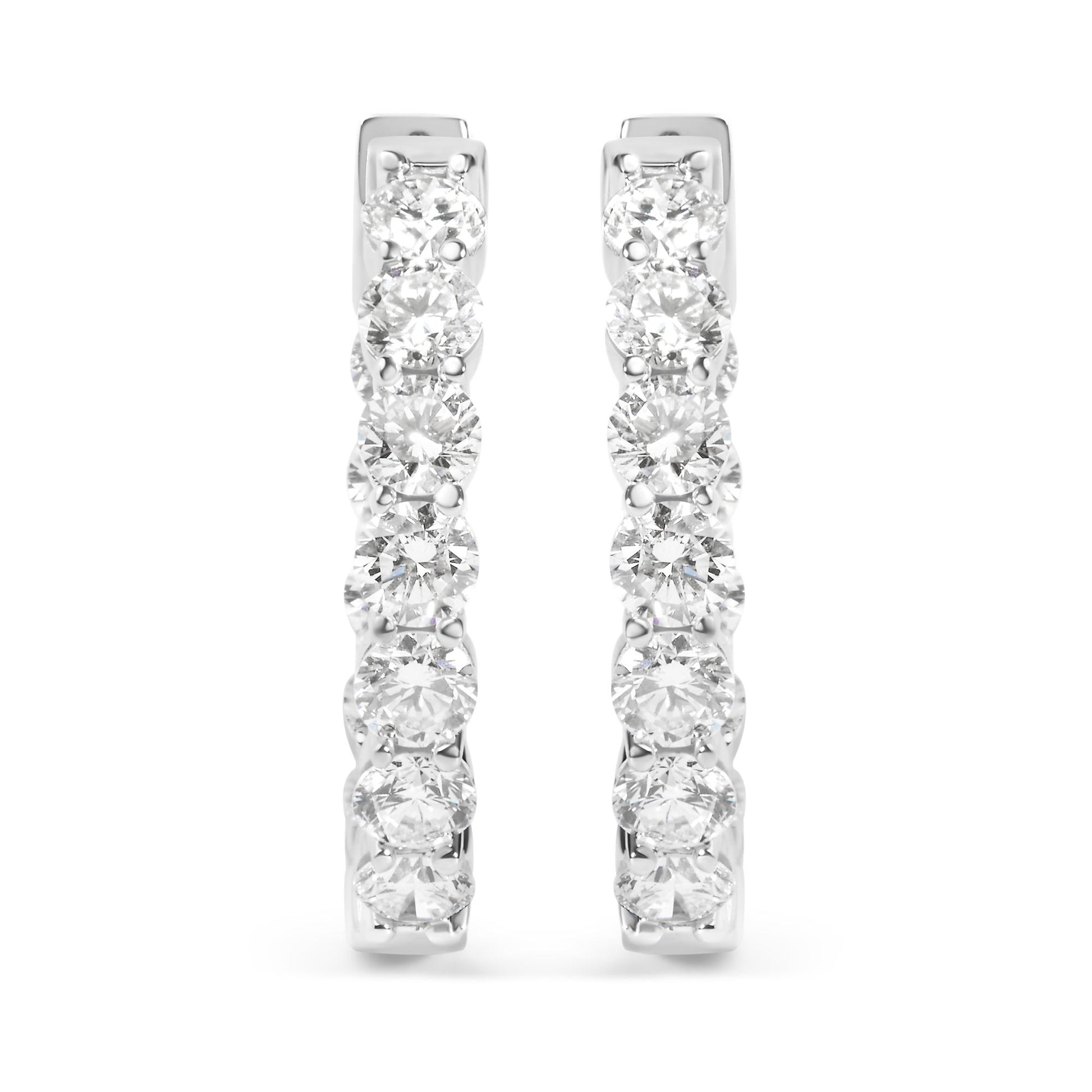 Front view of a pair of white metal hoop earrings set with multiple round white gemstones in a shared prong setting.