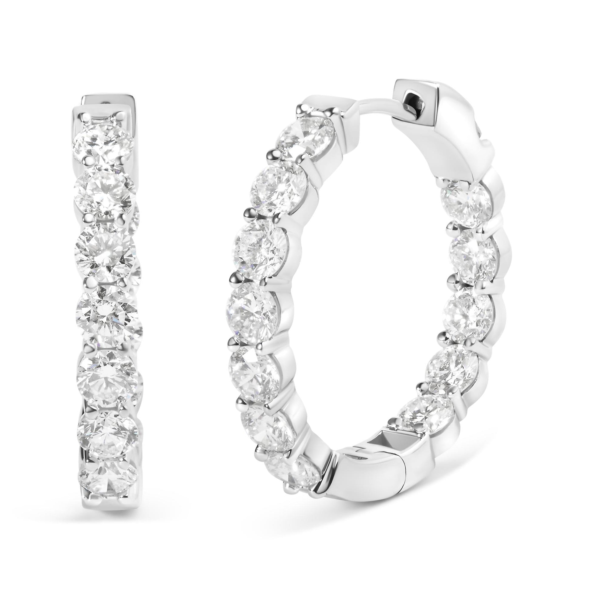 Pair of white metal hoop earrings with round white gemstones set along the outer edge in shared prong settings, shown at a front and angled side view on a white background.