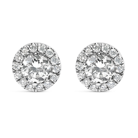Front-facing shot of round white metal stud earrings with a central round white gemstone surrounded by a halo of smaller round white gemstones.