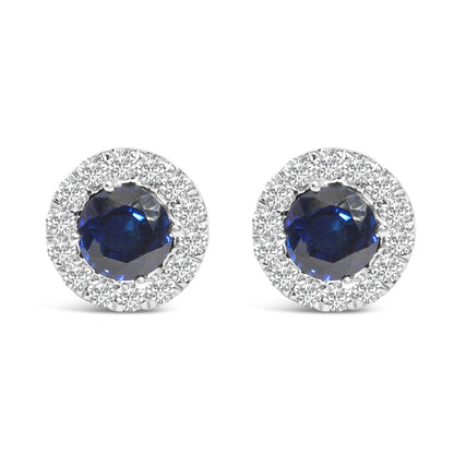 Pair of round white metal stud earrings with a large blue gemstone center, surrounded by a halo of small white gemstones, shown in a front-facing view on a white background.