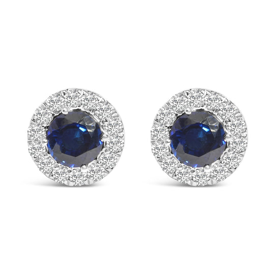 Pair of round white metal stud earrings with a large blue gemstone center, surrounded by a halo of small white gemstones, shown in a front-facing view on a white background.