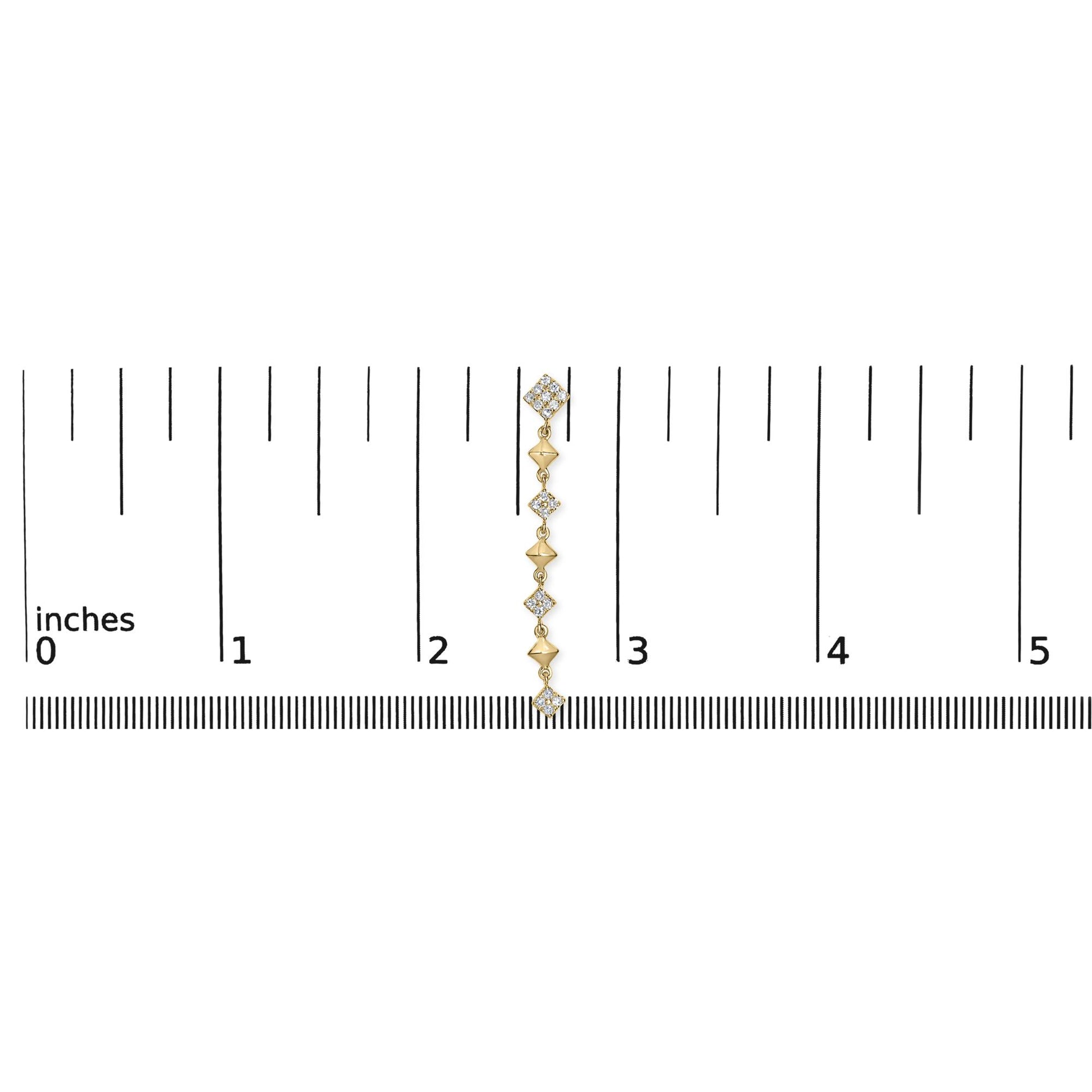 Yellow metal dangling earring with multiple white round gemstones in prong settings, shown on a ruler for size reference, front-facing angle.