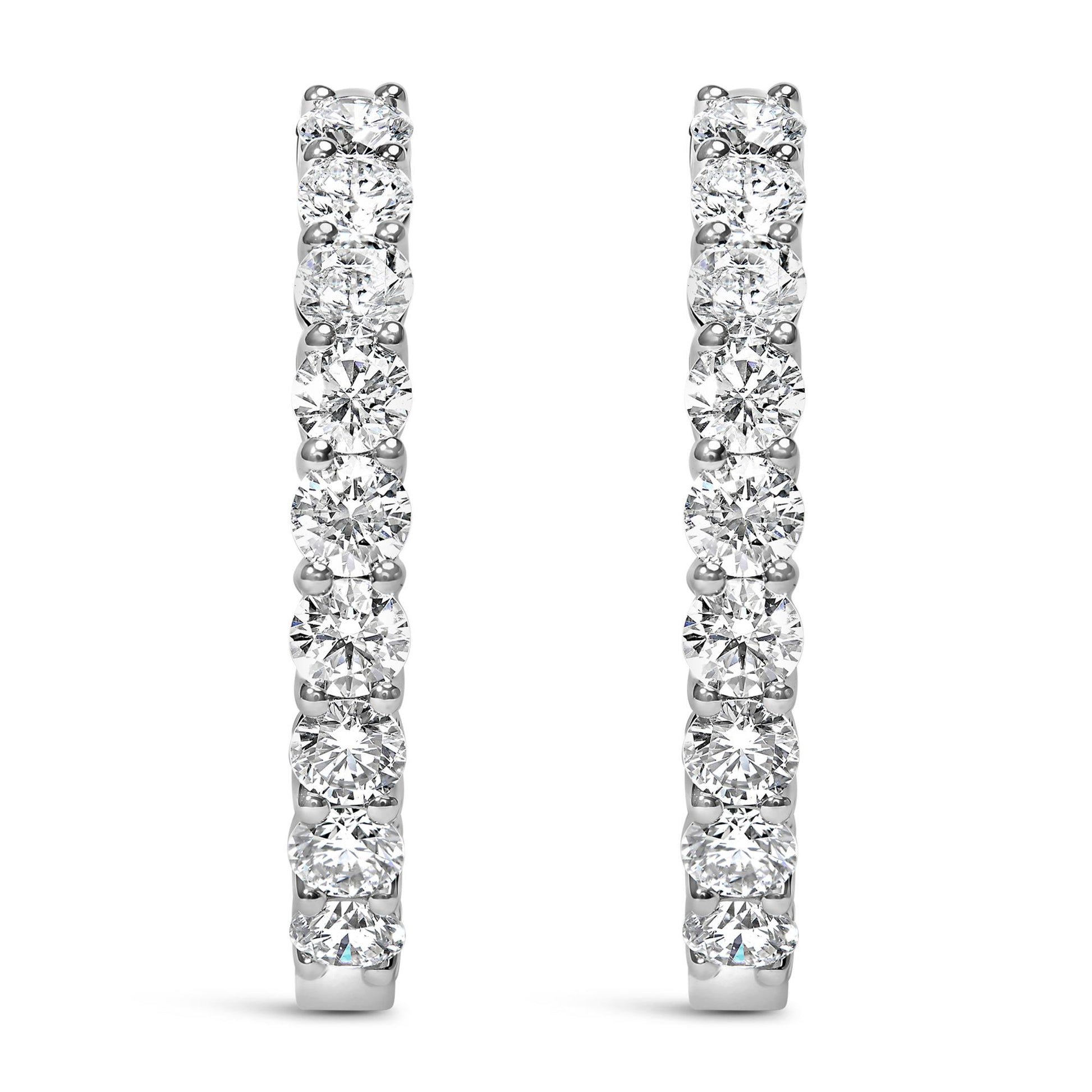 Front view of white metal hoop earrings set with round white gemstones in shared prong settings.