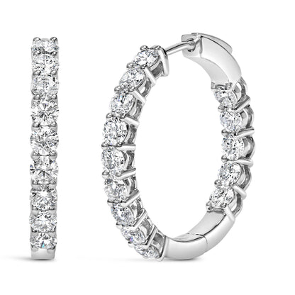 Close-up front and side view of white metal hoop earrings with round white gemstones in shared prong settings.