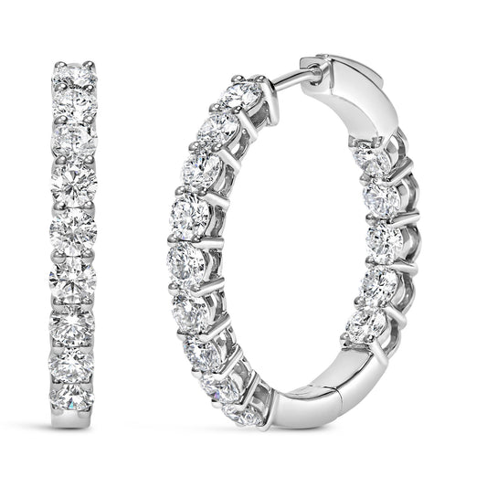 Close-up front and side view of white metal hoop earrings with round white gemstones in shared prong settings.