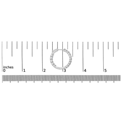 White metal hoop earring with round white gemstones in shared prong setting on a ruler for size reference, top-down angle.