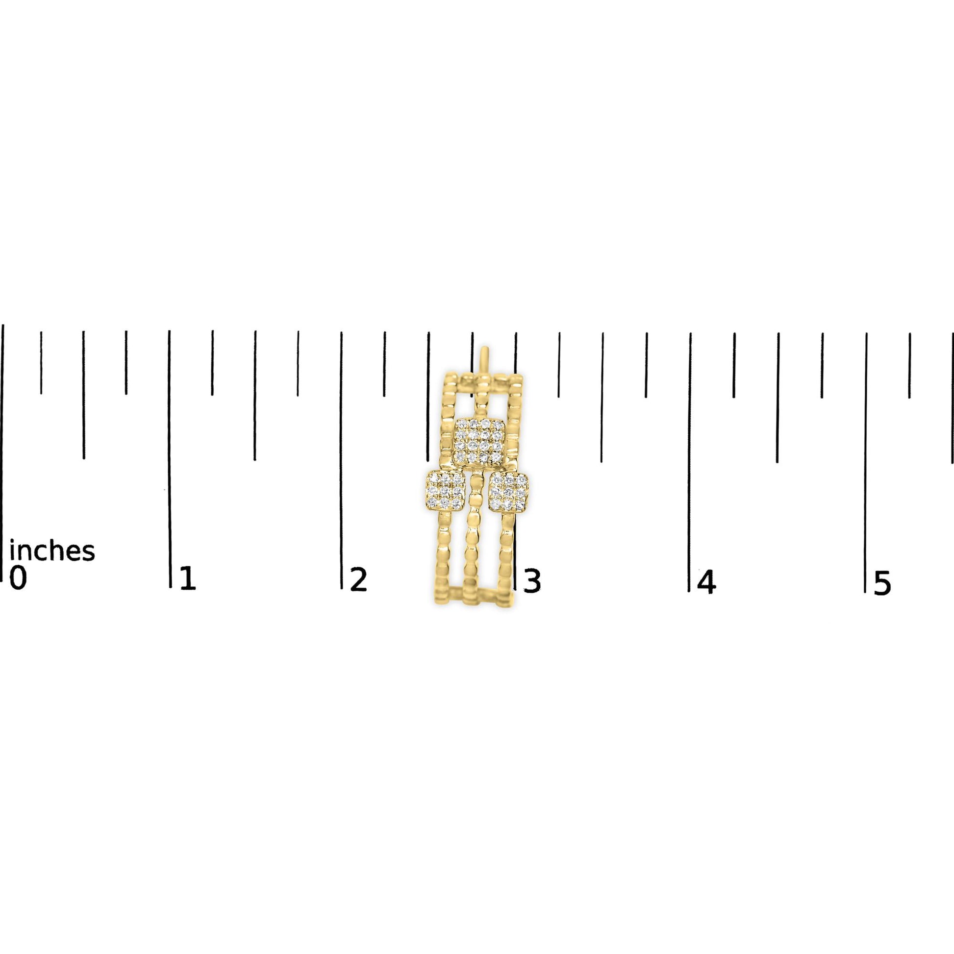 Earring with three rectangular yellow metal bands featuring clusters of round white gemstones, shown on a ruler from above.