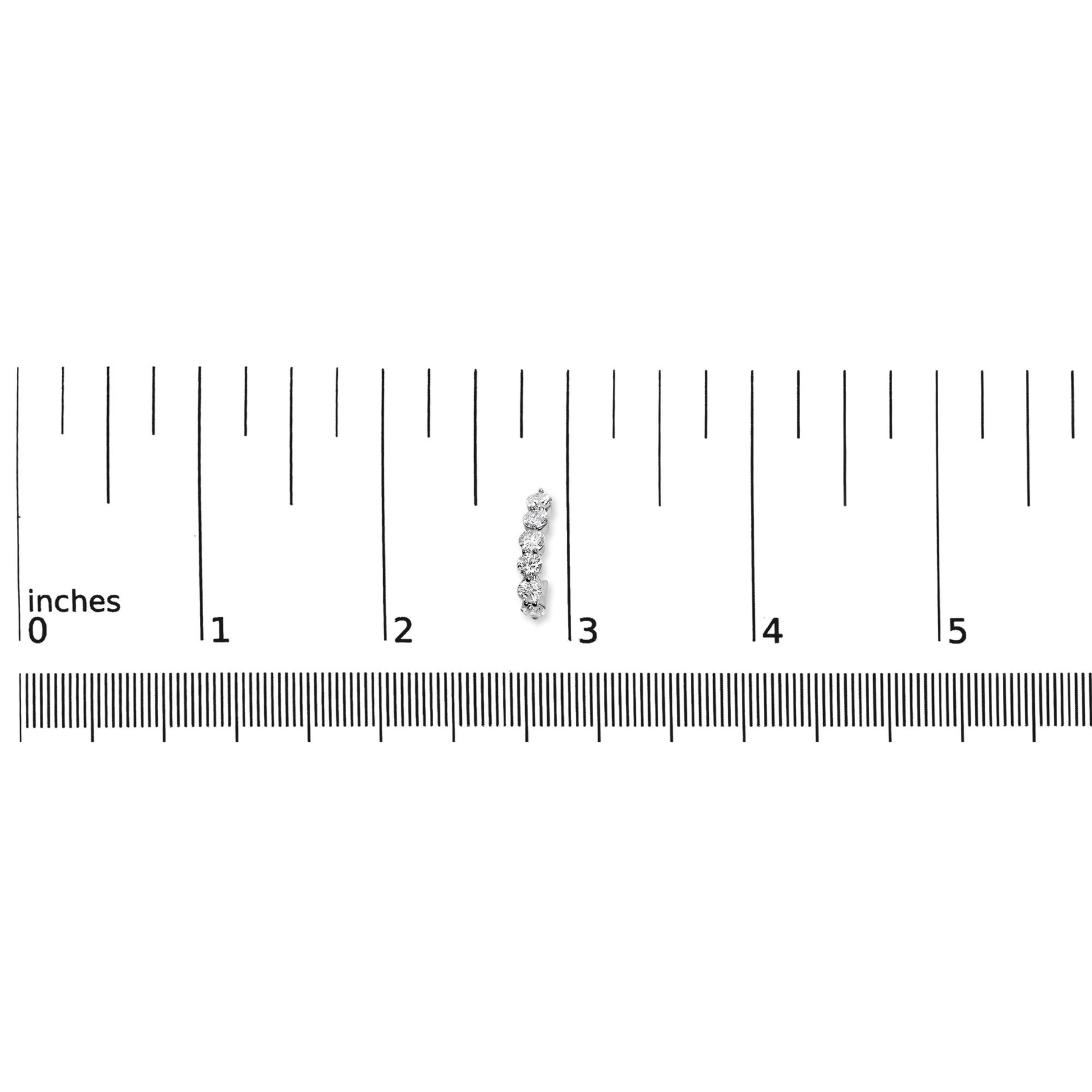 Close-up front view of a white metal earring with multiple round white gemstones in prong settings, placed on a ruler for size reference.