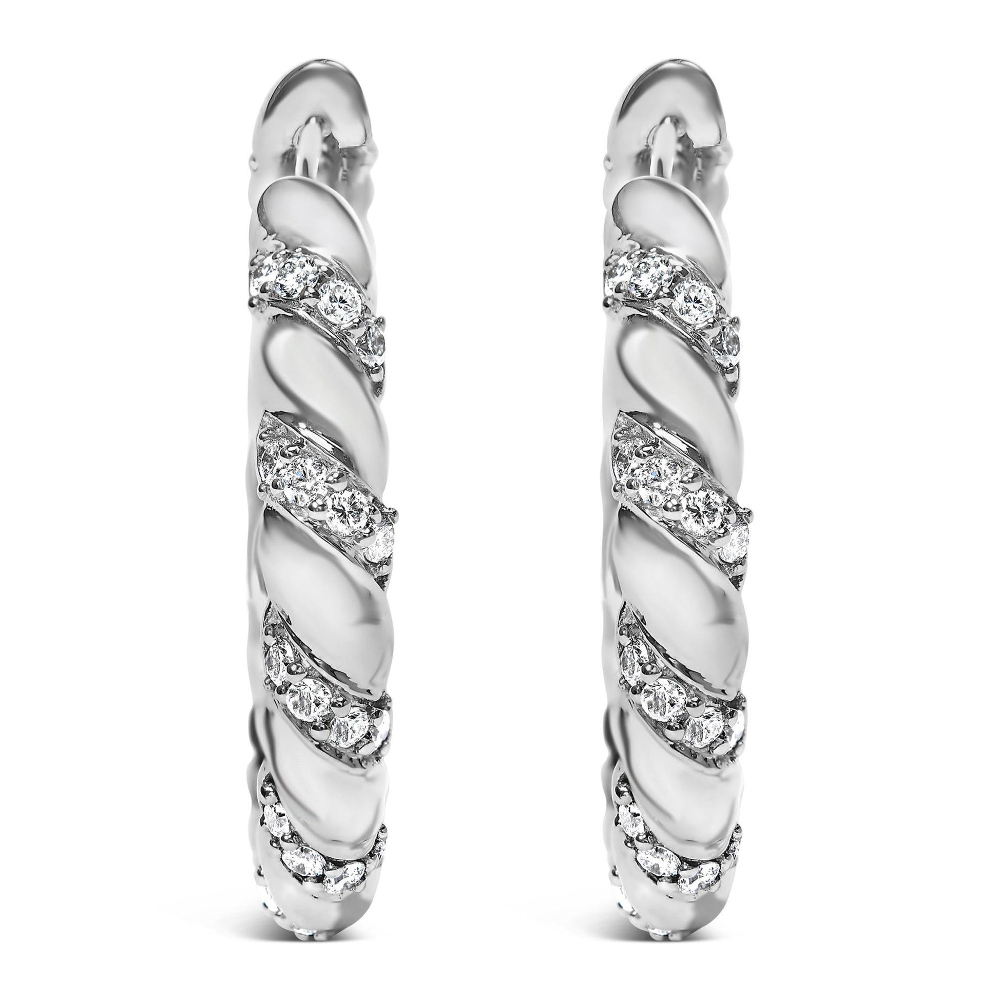 Front view of a pair of white metal hoop earrings with a twisted design featuring multiple rows of round white gemstones in prong settings.