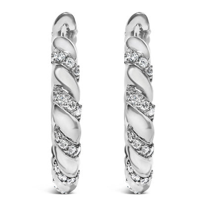 Front view of a pair of white metal hoop earrings with a twisted design featuring multiple rows of round white gemstones in prong settings.