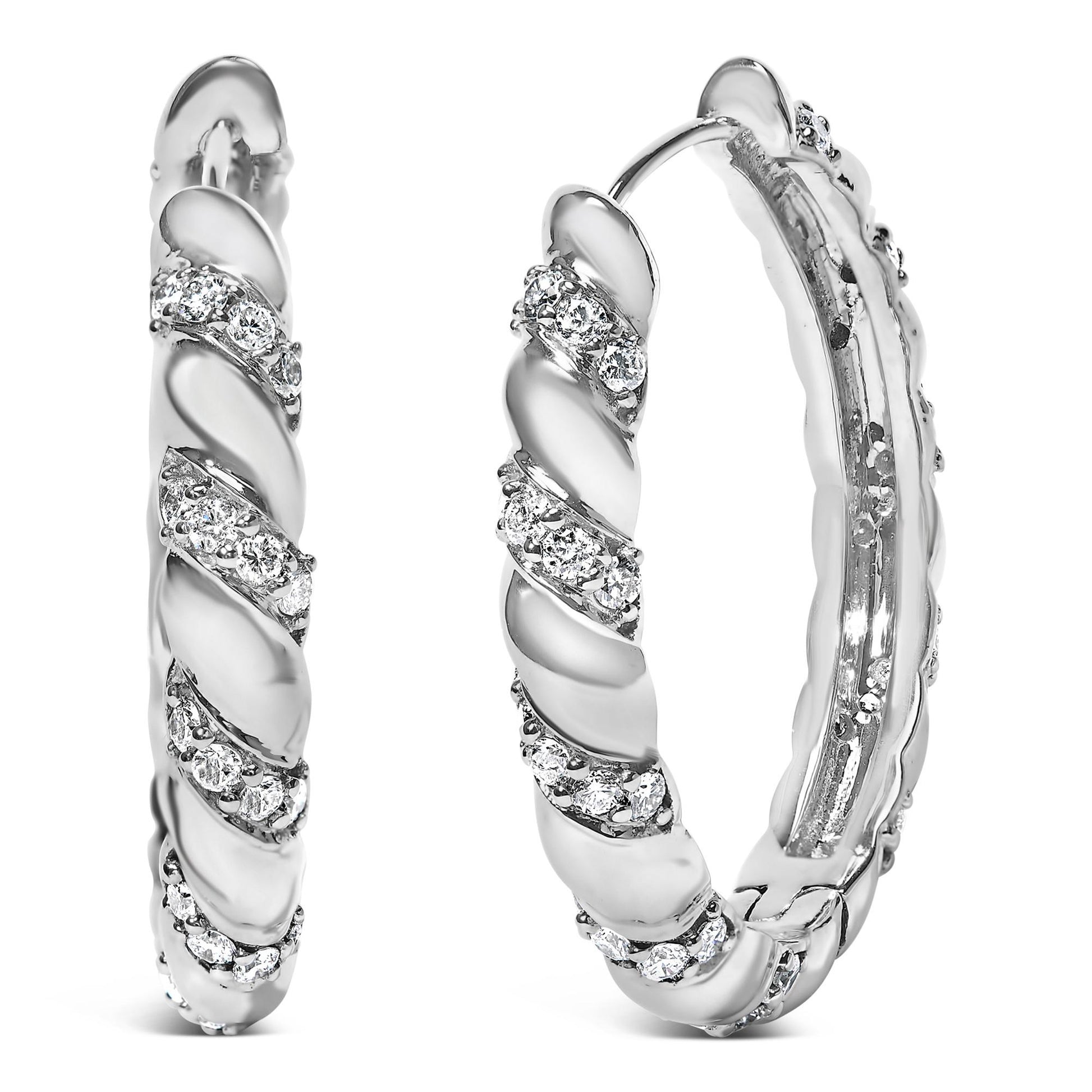 Front close-up angle of white metal hoop earrings with round white gemstones in prong settings arranged in a spiral pattern.