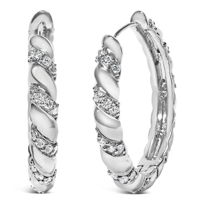Front close-up angle of white metal hoop earrings with round white gemstones in prong settings arranged in a spiral pattern.