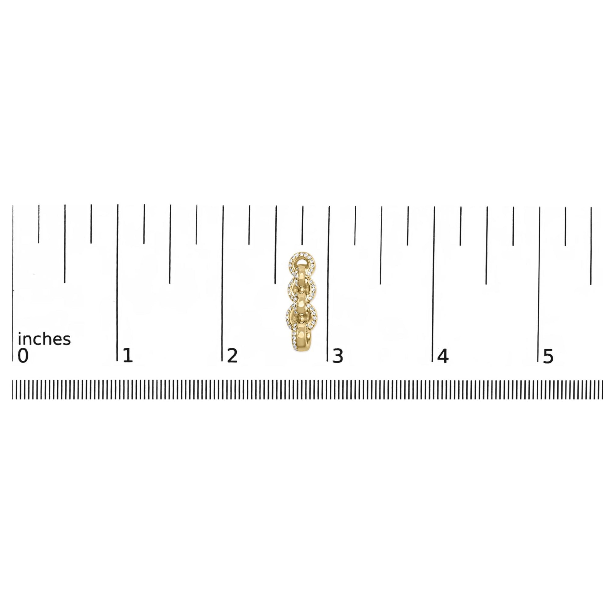 Close-up front view of a yellow metal earring with linked circular segments, each outlined with small white gemstones, placed on a ruler for size reference.
