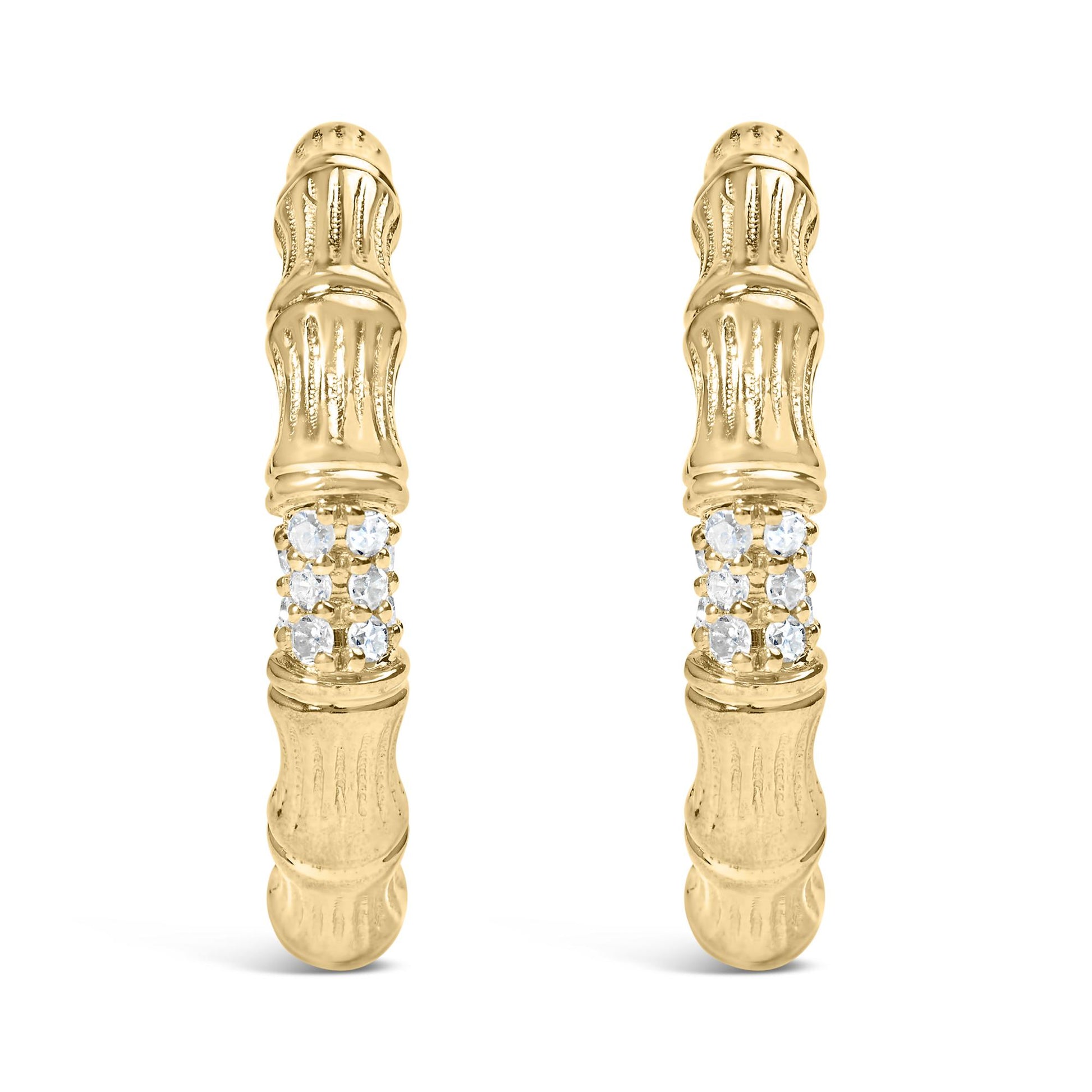 Front facing shot of a pair of yellow metal earrings with textured design and a cluster of round white gemstones in prong settings near the center.