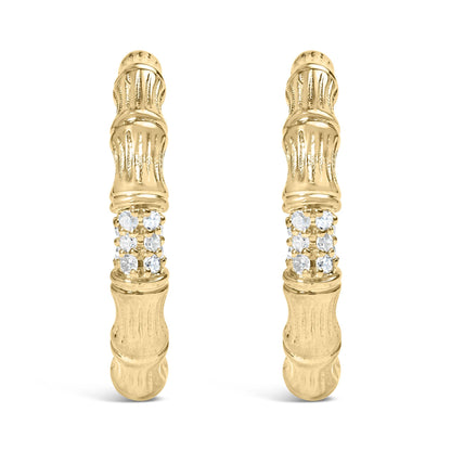 Front facing shot of a pair of yellow metal earrings with textured design and a cluster of round white gemstones in prong settings near the center.