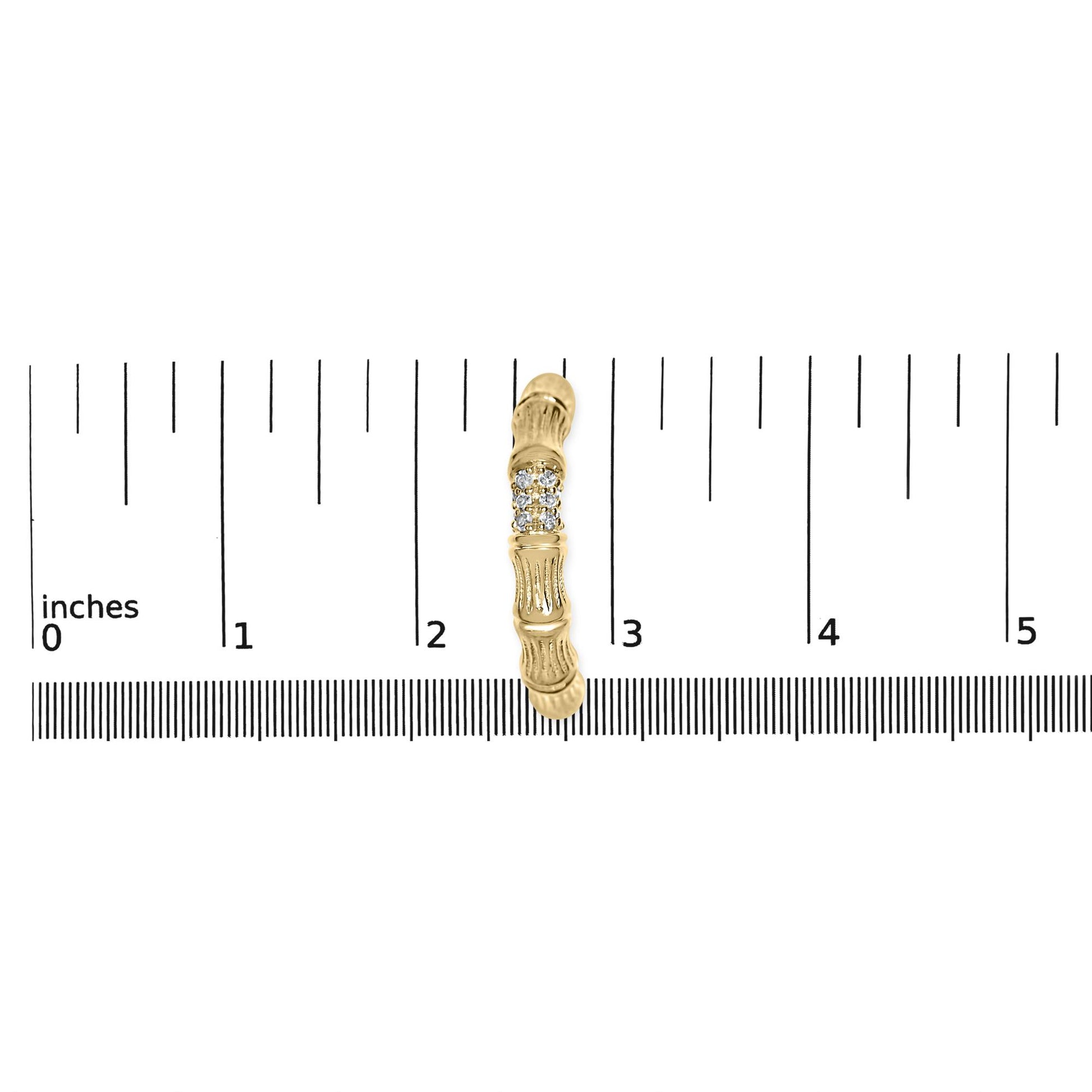 Single yellow metal earring with a row of round white gemstones, shown from the top on a ruler for size reference.