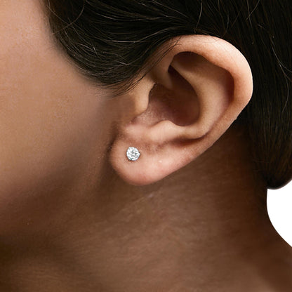 Close-up side angle of a model wearing white metal stud earrings with round white gemstones in a 3-prong setting.