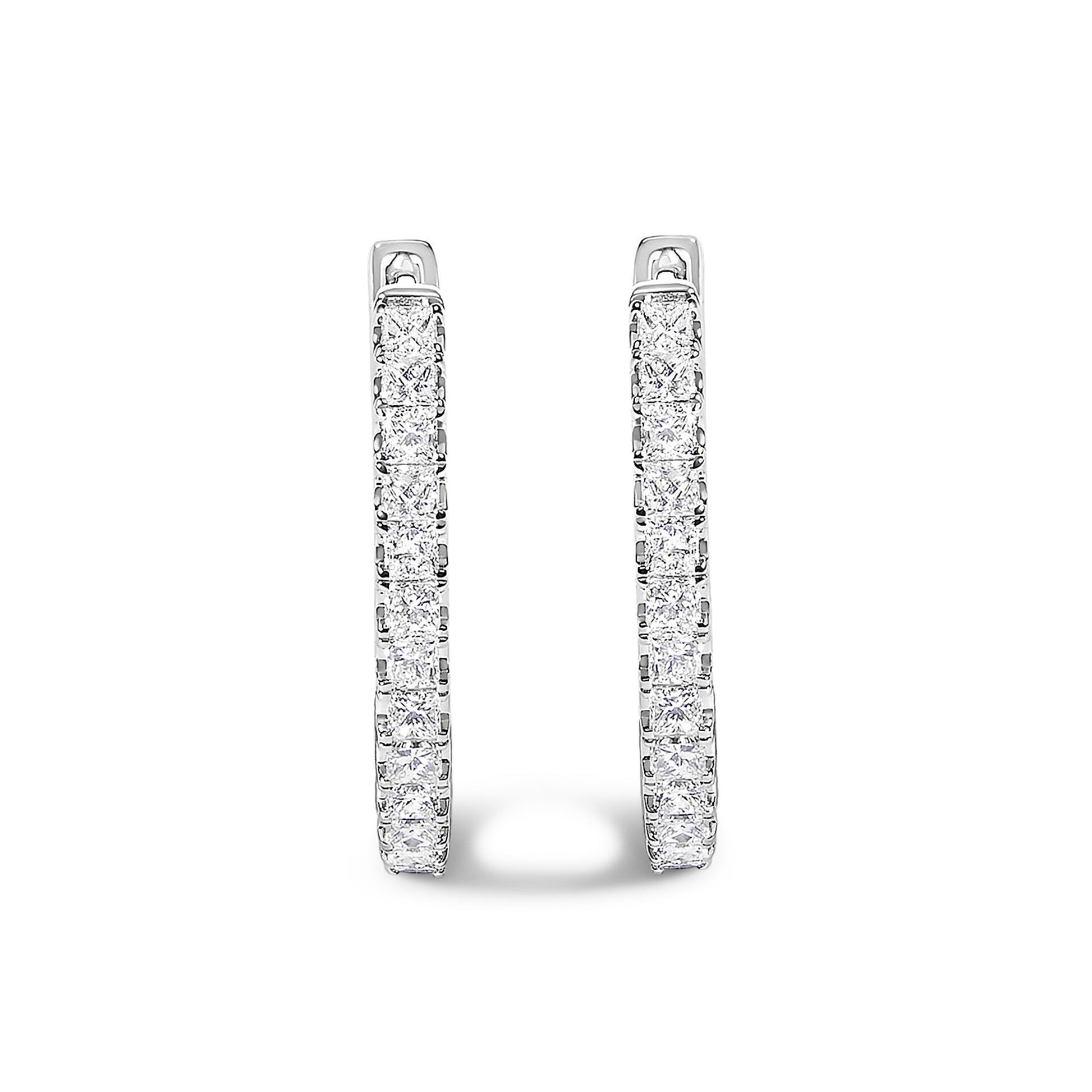 Pair of white metal hoop earrings with princess-shaped white gemstones in prong settings, shown in a front-facing close-up angle.