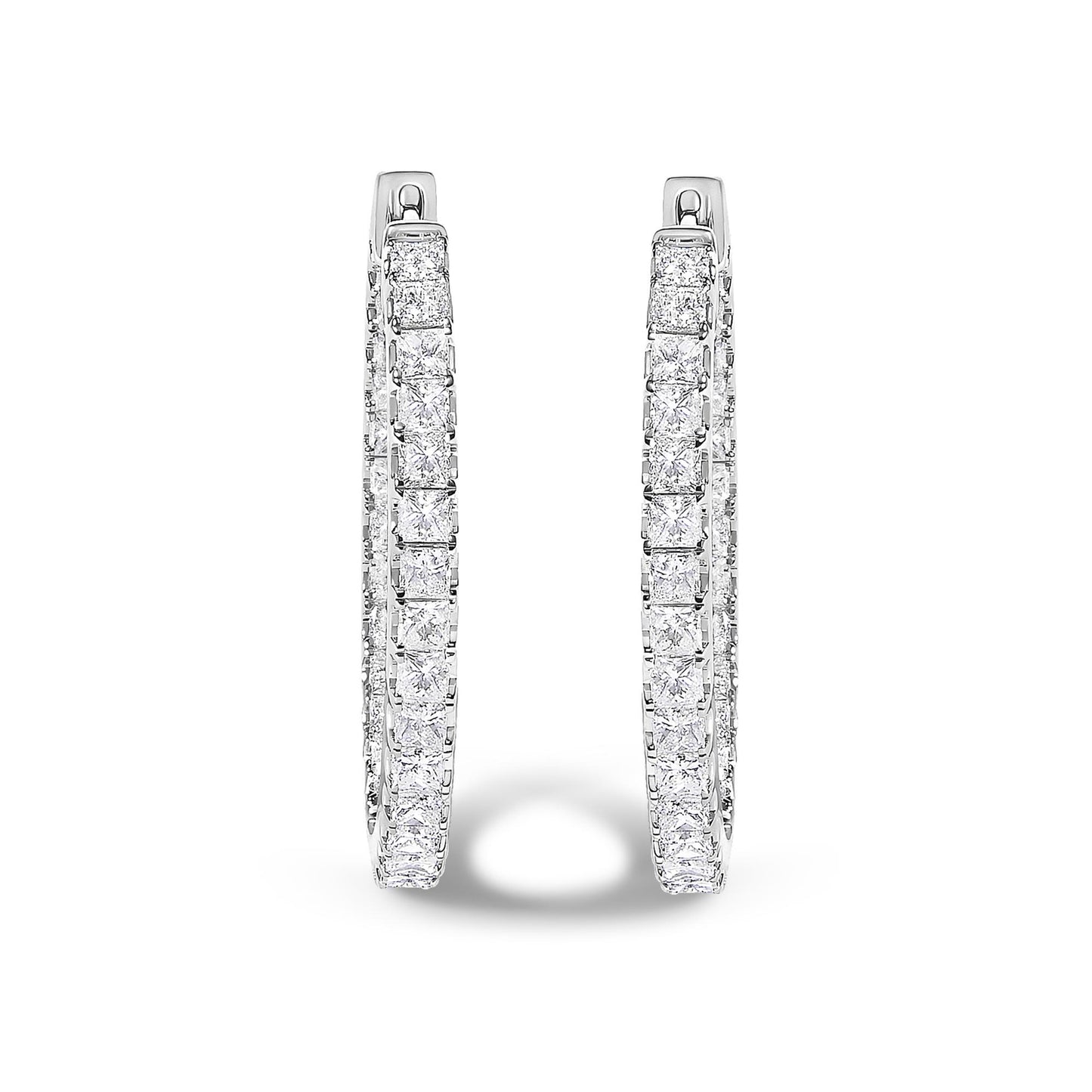Front-facing close-up of a pair of white metal hoop earrings adorned with princess shaped white gemstones in a prong setting.