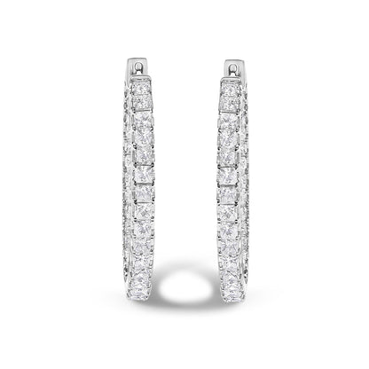 Front-facing close-up of a pair of white metal hoop earrings adorned with princess shaped white gemstones in a prong setting.