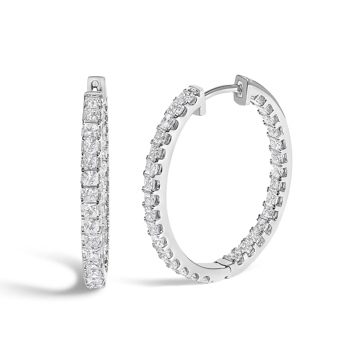 Close-up front angled view of a pair of white metal hoop earrings set with multiple princess-shaped white gemstones in a prong setting.
