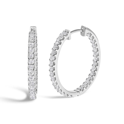 Close-up front angled view of a pair of white metal hoop earrings set with multiple princess-shaped white gemstones in a prong setting.