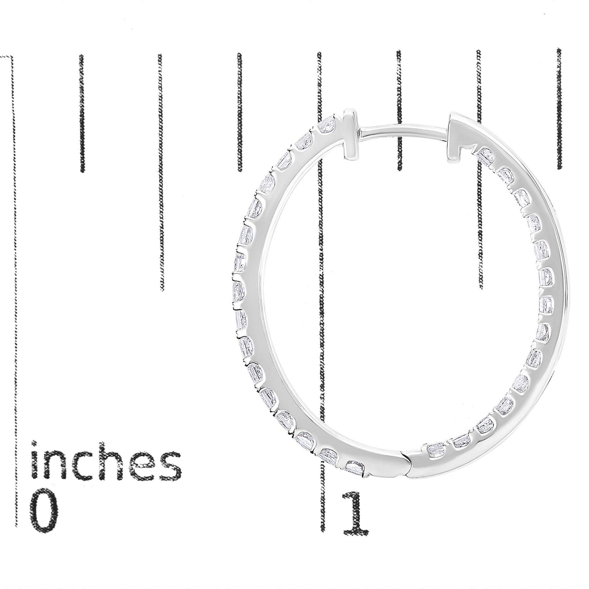 Close-up front view of a white metal hoop earring with white princess-shaped gemstones in prong settings, shown on a scale with inch markings.
