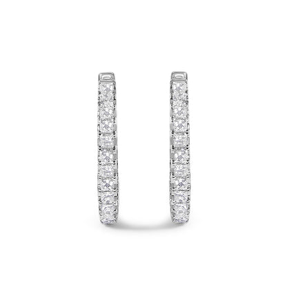 Close-up front view of a pair of white metal hoop earrings set with rows of princess-shaped white gemstones in prong settings.