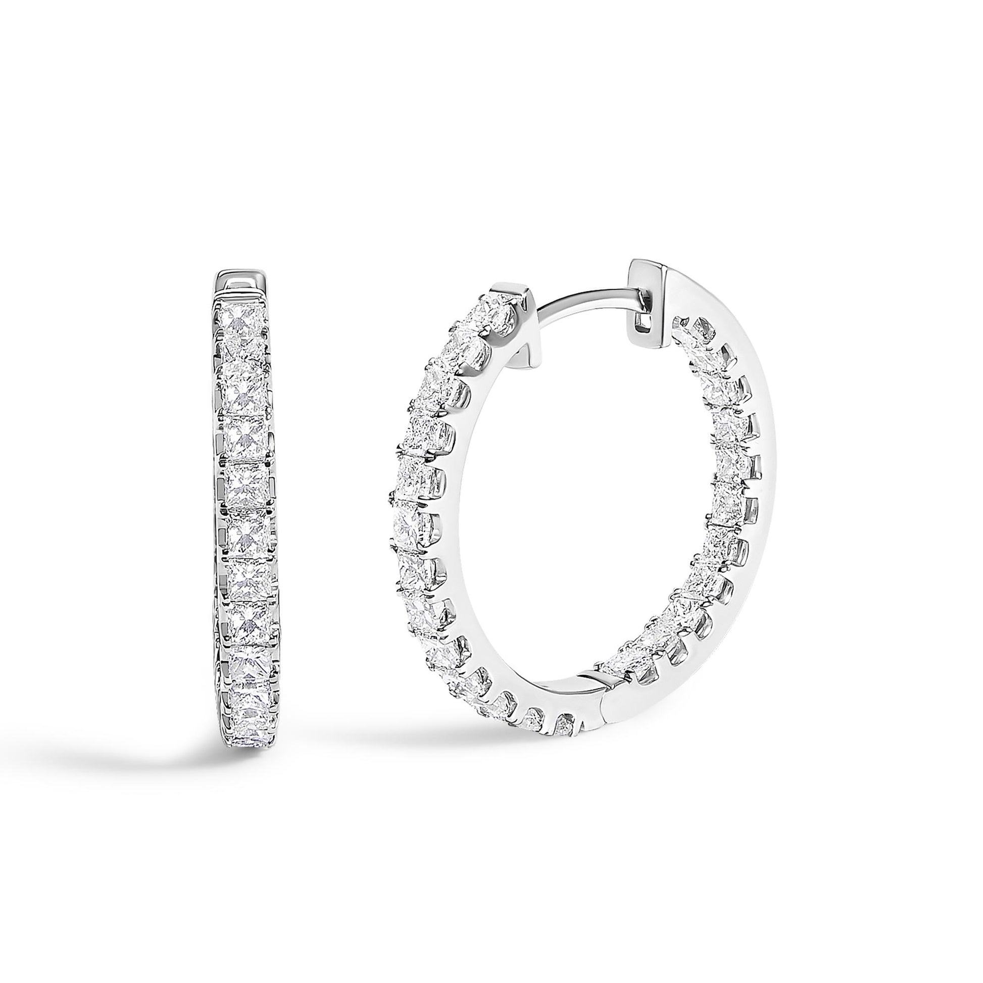Close-up front and side angle of white metal hoop earrings featuring princess shape white gemstones in prong settings along the outer edge, shown on a white background.