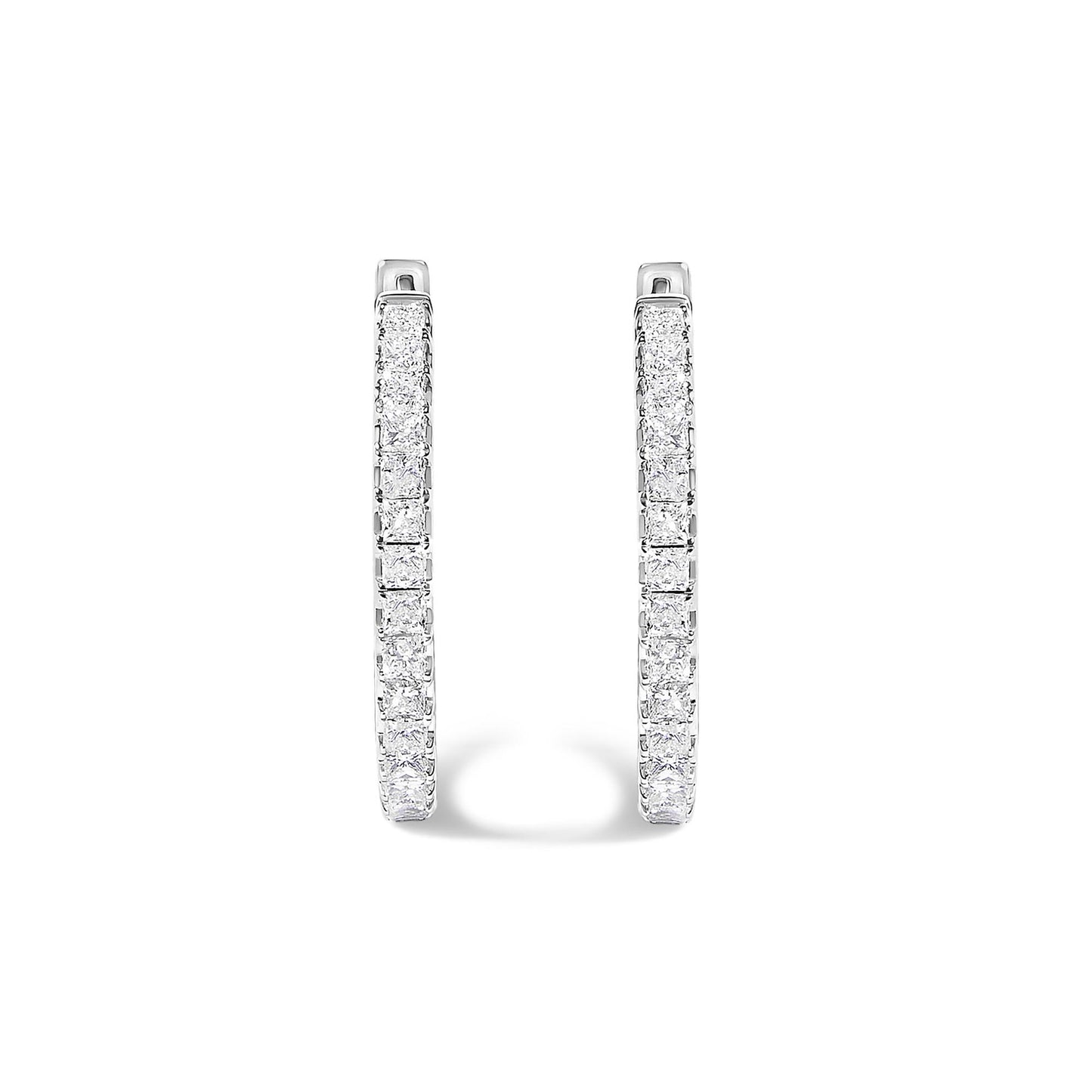 Close-up front view of a pair of white metal hoop earrings featuring princess-shaped white gemstones set in prong settings along the outer curves, shown on a white background.