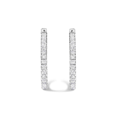 Close-up front view of a pair of white metal hoop earrings featuring princess-shaped white gemstones set in prong settings along the outer curves, shown on a white background.