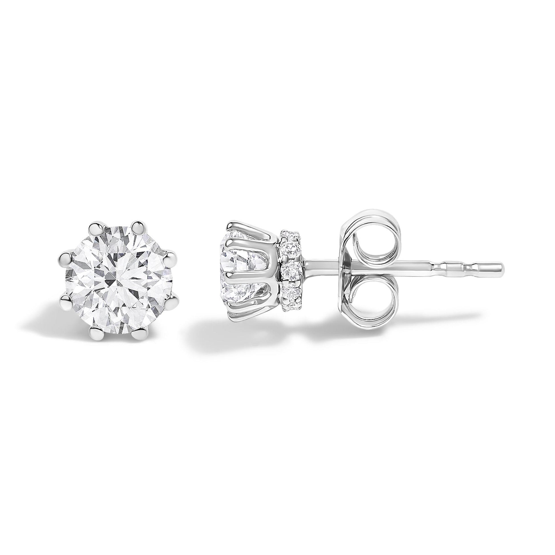 Pair of white metal stud earrings shown in front and side angles, featuring a large round white gemstone in a prong setting with smaller round white gemstones surrounding the base.