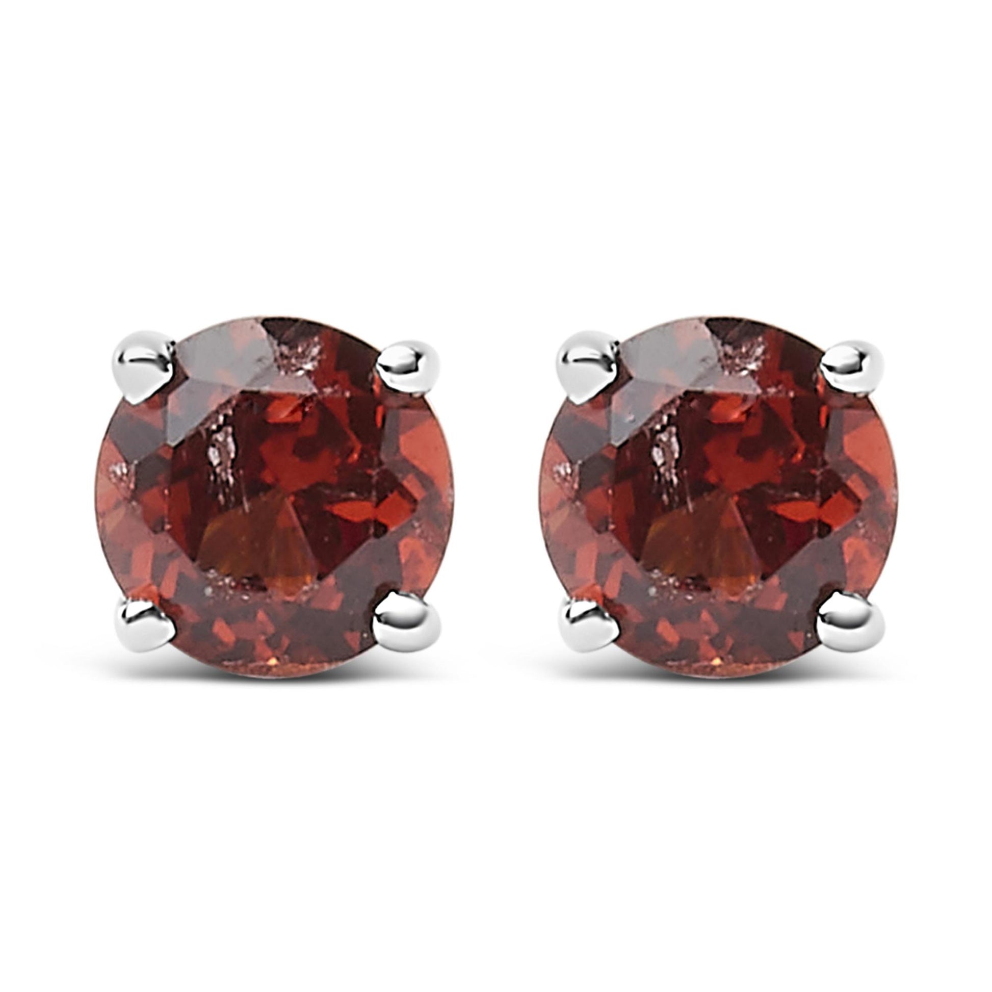 Front view of a pair of white metal stud earrings each set with a round red gemstone in a 4-prong setting.