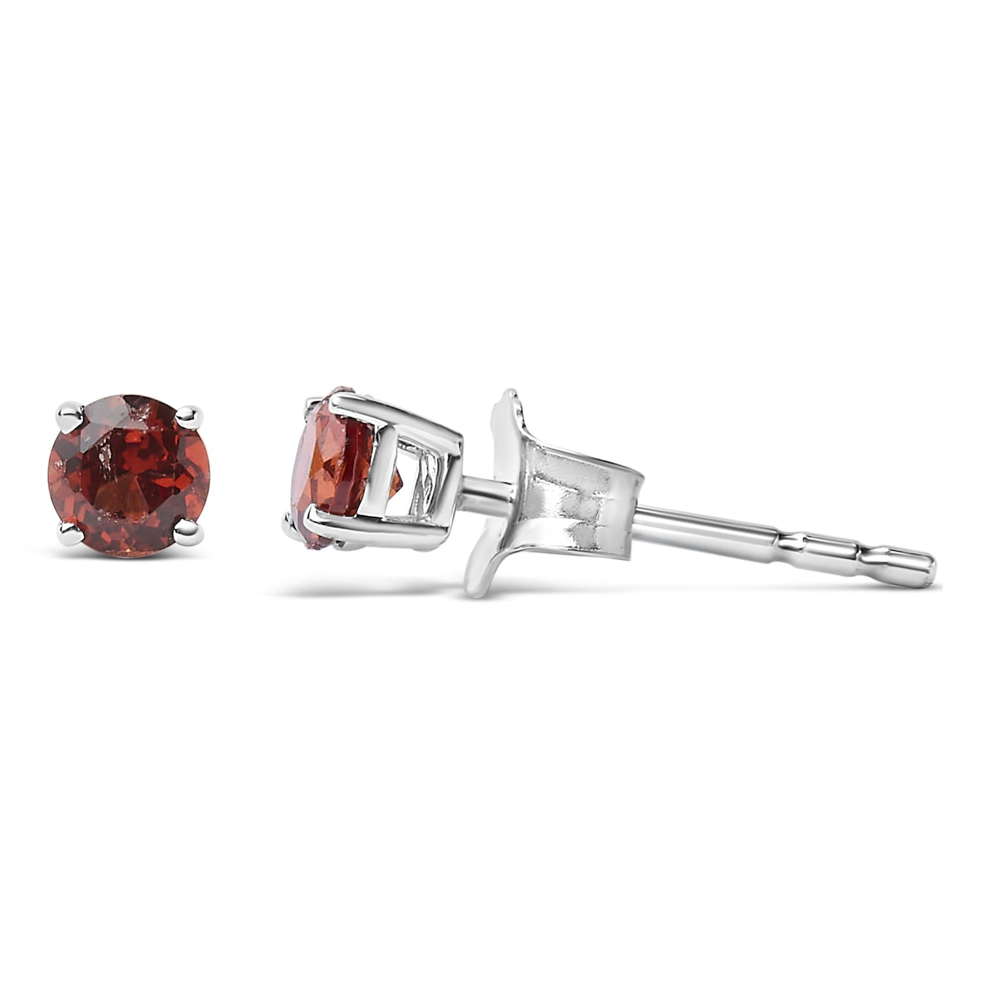 Close-up side angle of white metal stud earrings with round red gemstones in four-prong settings.