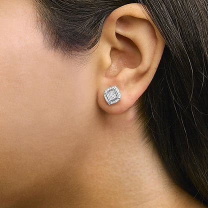 Close-up side view of a model wearing white metal stud earrings featuring princess-shape white gemstones with invisible settings surrounded by round white gemstones in prong settings.