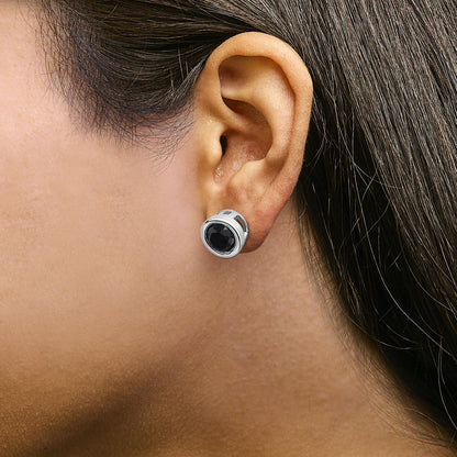 Close-up side view of a model wearing a round bezel-set black gemstone white metal stud earring.