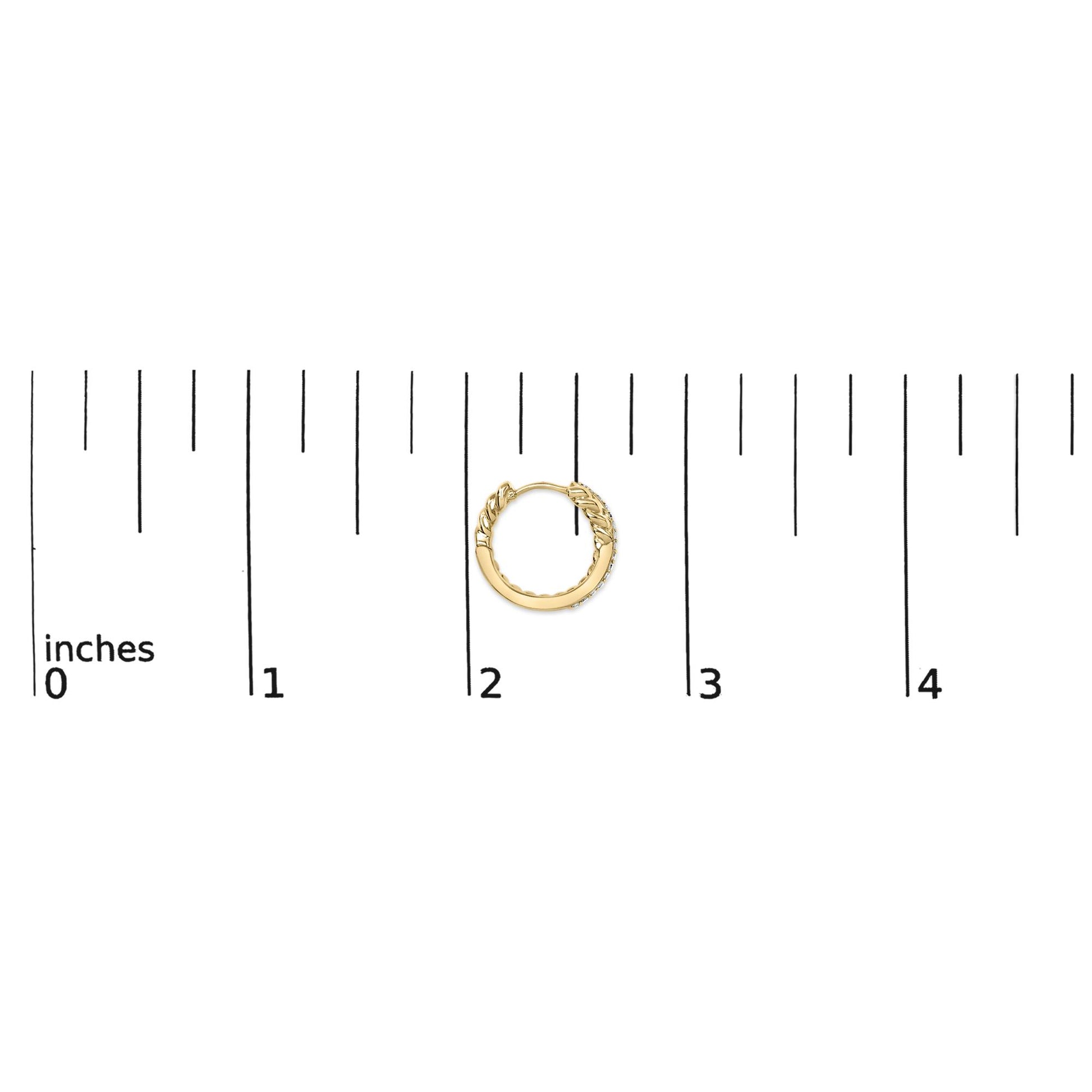 Close-up overhead view of a single yellow metal hoop earring with a twisted design and small white gemstones set in prongs along the outer edge, shown on a scale in inches.