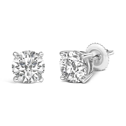 Pair of white metal stud earrings with round white gemstones in four-prong settings, one shown from the front and the other at a side angle.