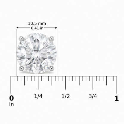 Close-up front view of a white metal stud earring with a round white gemstone in a four-prong setting, shown on a scale.