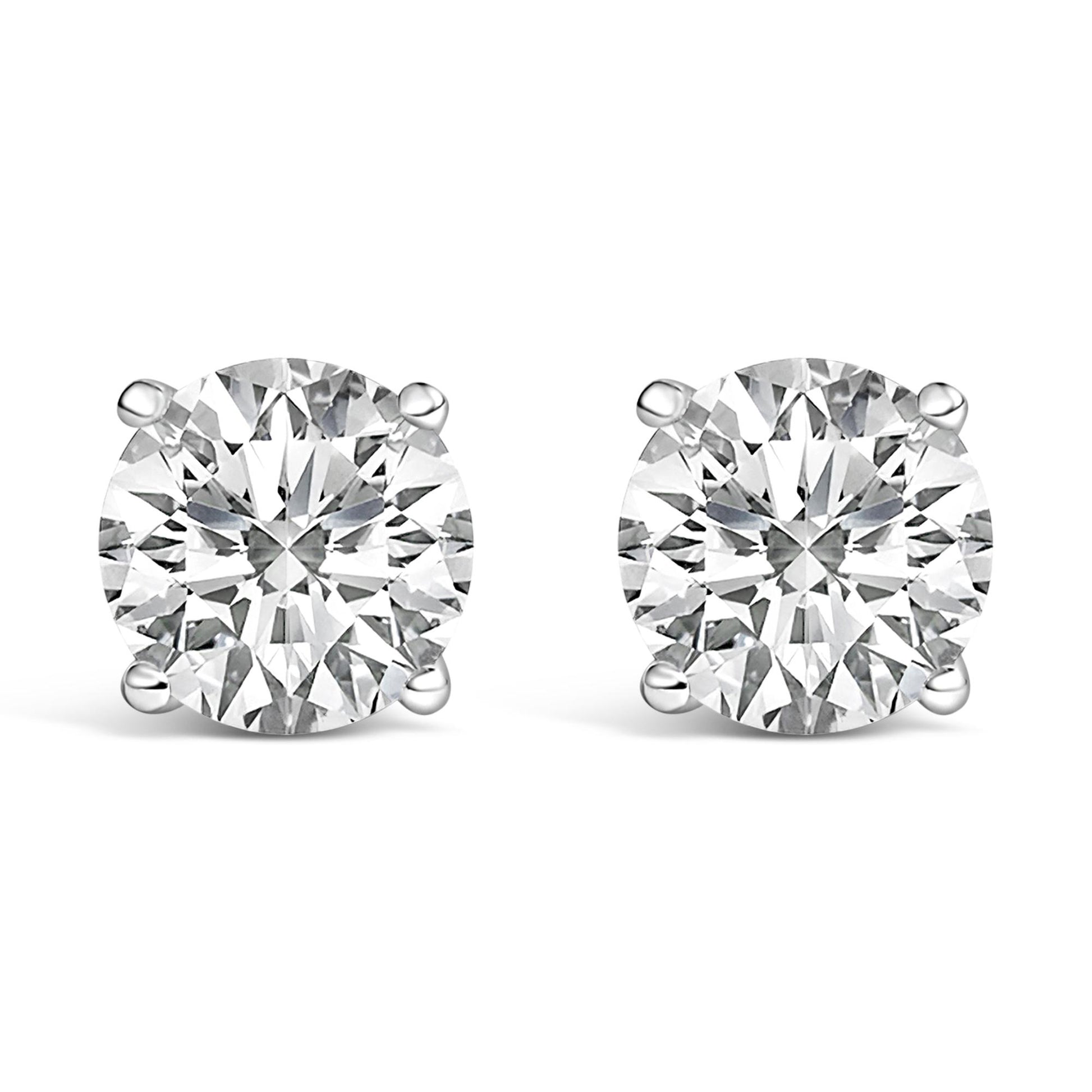 Close-up front angle of a pair of white metal stud earrings, each featuring a round white gemstone secured by a four-prong setting.