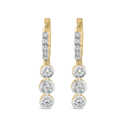 Close-up front view of a pair of yellow metal earrings featuring multiple round white gemstones in prong and bezel settings along the vertical length.