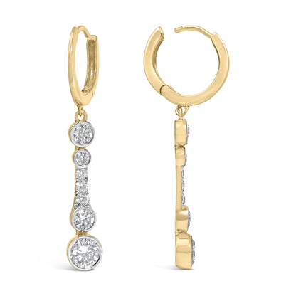 Close-up front and side view of a pair of yellow metal hoop earrings with dangling white gemstones in bezel and prong settings.