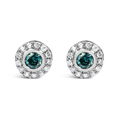 Close-up front view of a pair of white metal round stud earrings each featuring a central round blue gemstone surrounded by a halo of round white gemstones in prong settings.