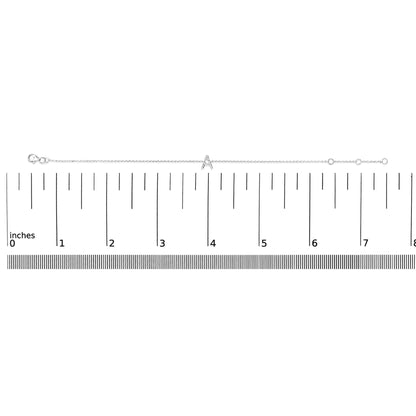 White metal bracelet with a central 'A' charm adorned with small white gemstones in a micro-pave setting, shown laid flat on a ruler for scale, image taken from a top-down angle.