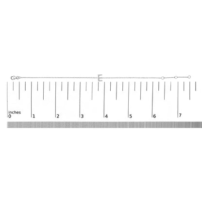 White bracelet with a chain and a central letter 'E' adorned with small round white gemstones in a micro-pave setting, shown on a ruler scale from a top-down angle.
