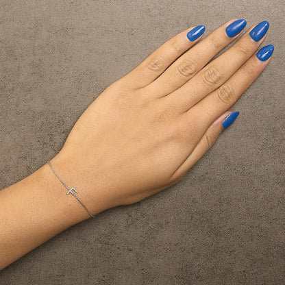 Bracelet with a delicate white chain and a horizontal bar set with small white gemstones, shown on a model's wrist, top-down angle.