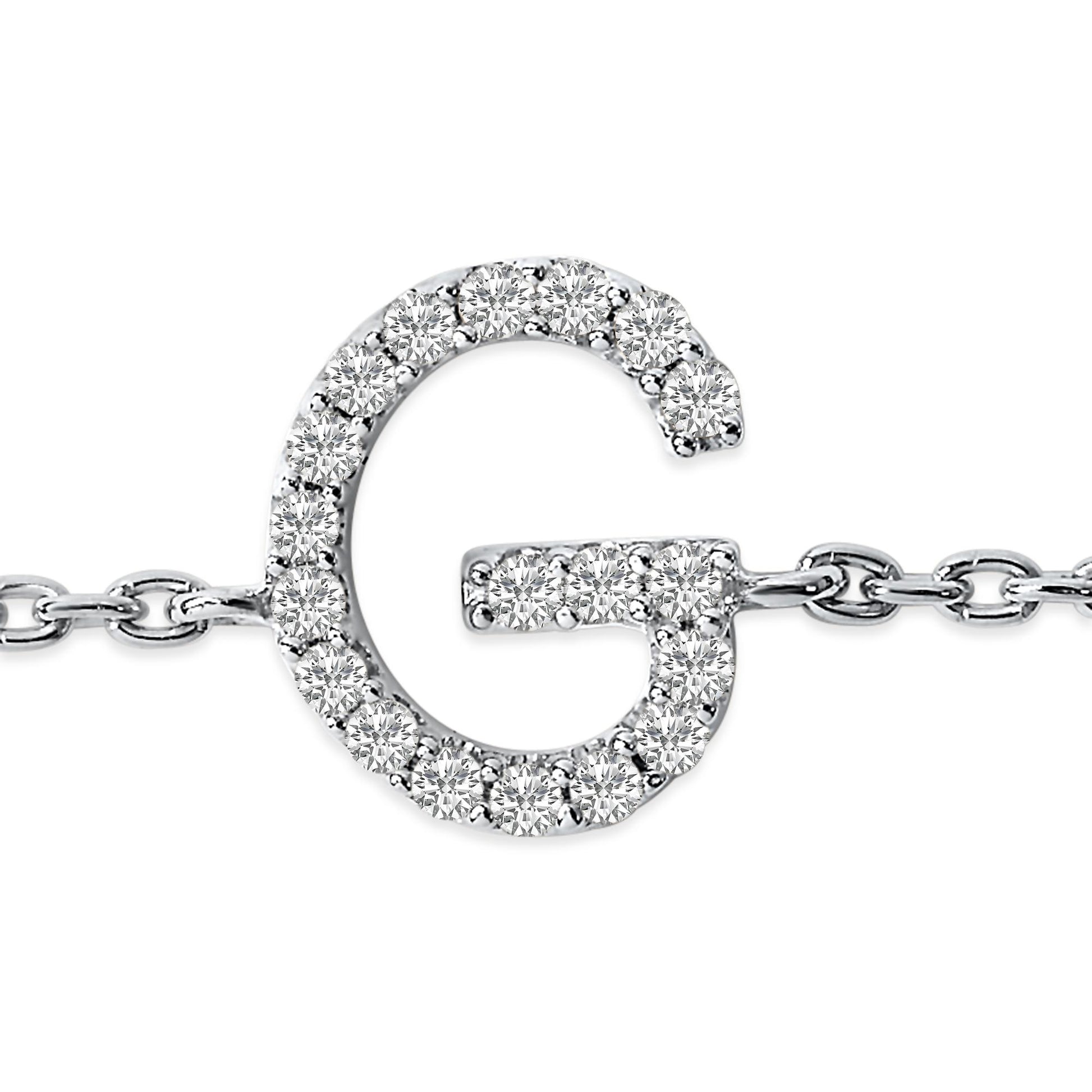 Close-up front view of a white metal bracelet featuring a 'G' shaped charm adorned with small round white gemstones in a micro-pave setting, attached to a link chain.
