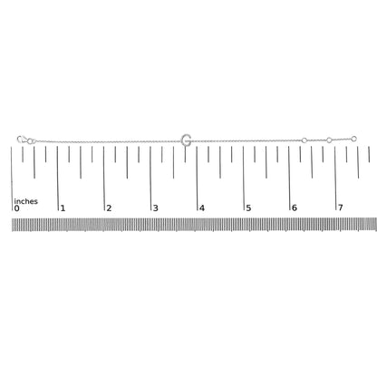 White bracelet with a micro-pave set round white gemstones forming a letter shape, shown flat on a ruler for scale, top-down angle.