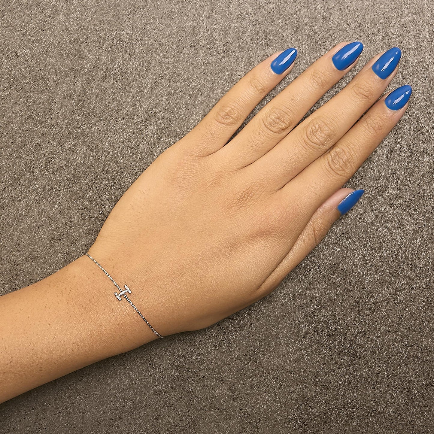 Bracelet with a thin white chain and a horizontal bar adorned with small round white gemstones in a micro-pave setting, shown worn on a model's wrist from a top angle.